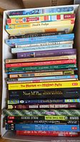 Top view of children's books, spines visible showing titles and authors, stacked inside a box.