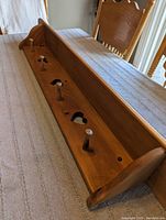 Top view of the pine wooden shelf showing five wooden pegs and three heart cutouts along the back panel.