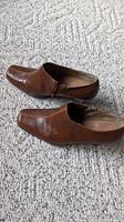 Pair of rust colored ladies ankle boots laid on carpet, showing profile and square toe shape.