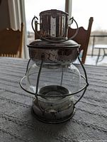 Silver weathered lantern with visible rust and metal handle, placed on grey textured surface