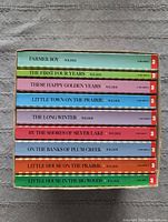 Stack of 9 Laura Ingalls Wilder books showing titles and condition, spines visible to confirm set and series.