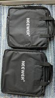 Two black Neewer branded storage bags laid flat on a carpeted surface.