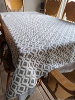 Tablecloth spread across a wooden dining table showing full coverage and pattern detail.