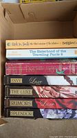 Photo of seven young adult paperback books packed upright in a box, showing spines: Girls in Pants, Sisterhood of the Traveling Pants 2 & 3, Inkheart, and Luxe series books by Anna Godbersen.