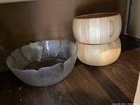 Three salad bowls together on shelf: two light wood round bowls stacked, one clear glass scalloped bowl nearby