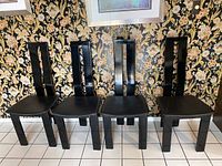 Front view of all four chairs in a row on tiled floor against patterned wallpaper