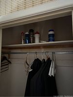 Photo of closet shelf with five assorted water bottles of different colors and sizes.