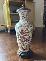 Full view of tall porcelain vase with bird and foliage decoration fitted on an aged patinated metal base and topped with a matching metal lid, showing overall condition and size.