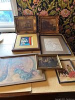 Overview of seven framed art pieces showing different styles including floral prints, paintings, sketches, and portraits. Frames show visible wear and some chips.