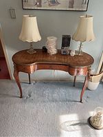 Full view of kidney-shaped Louis XV style desk with items on top illustrating size and wear.