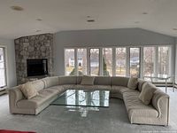 Full view of curved modular sofa in room setting with coffee table (not included) showing all five sections and four pillows.