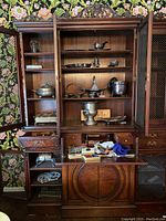Full view of the cabinet with silverplate items displayed on shelves and miscellaneous contents in the bottom section, showcasing all items included in the lot.