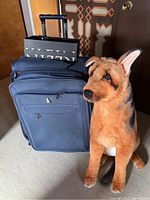 Photo showing large navy blue suitcase and large stuffed dog toy