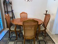 Full view of wooden dining table with four matching chairs around it, showing parquet top and chair caning.