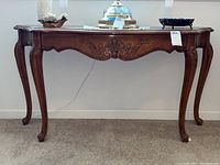 Front view of the Hammary foyer table showing the curved legs and carved apron with shell motif.