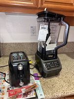 Photo showing both the Ninja Professional Blender Pro 1000 and a black two-slice toaster on a kitchen counter.