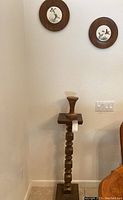 Full view of wooden pedestal stand with candle holder on top, showing height and shape.