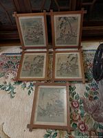 Five framed Japanese silk paintings arranged on carpet. One frame has cracked glass.