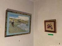 Photo showing two framed art pieces on adjacent walls: larger fly fishing scene and smaller botanical fruit illustration.