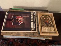 Photo showing The Illustrated London News dated February 6, 1965 and Coronation souvenir programme for Queen Elizabeth II, with extra maps partially visible underneath.