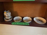 Four pieces of Birks china including one taller piece and three small dishes with gold floral patterns on shelves