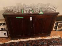 Front view of the vintage hardwood buffet with glassware arranged on top, showing condition and size