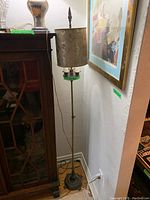 Full view of the standing floor lamp beside furniture in corner of room showing height, base, and shade.