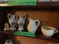 Full shelf view showing 2 painted ceramic vases, 2 white Irish china pieces, and silver plated bell