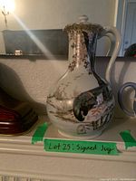 Front view of the signed ceramic jug showing the bird illustration and lid