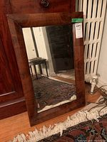 Full view of the mirror resting against furniture showing the rectangular shape and wood frame.