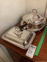 Photo showing the warming dish with black handle and oval tray side by side on a wooden surface.