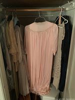 Full view of hanging garments including pink silk peignoir and beige lace dress