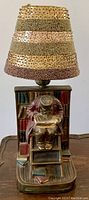 Front view showing scholar figure seated on ladder, bookshelves behind, and beaded lampshade.