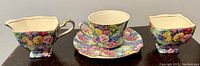 Photo showing side view of the 4-piece Royal Winton Julia chintz tea set: creamer, teacup on saucer, and sugar bowl with colorful floral pattern.