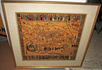 Frontal photo of the framed antique Oxford map showing the colorful heraldic and historic figures on top and bottom borders with a beige mat and gold frame.