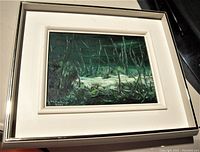 Framed oil painting on canvas, showing a forest landscape scene with dark green tones. The signature of the artist Helene Poliot Rioux can be seen on the painting.