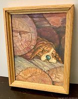 Frontal view of the framed oil painting showing a sleepy Basset Hound resting on wooden logs, signed by P Chan.