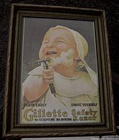 Front view of framed vintage Gillette Safety Razor advertising print featuring a baby holding a razor with shaving cream on its face.