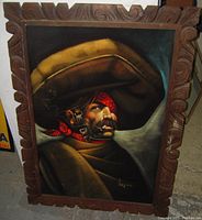 Front view of vintage bandito man portrait painting on black velvet with detailed carved Spanish wood frame, signed Lopez