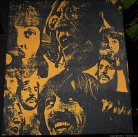 Close-up front view of Beatles fabric art with orange and black batik style portraits.