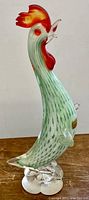 Side view of the Mod Era signed Murano glass rooster statue showing green body with red comb and clear glass base.