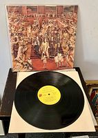 Front cover of the first "It's Only Rock & Roll" LP with the vinyl record placed on a white inner sleeve in front of it, showing the iconic group photograph artwork.