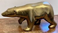 Right side profile of brass polar bear sculpture on wood surface