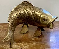 Front side view showing detailed scales, fins, and arched body of the brass koi fish sculpture with open mouth.