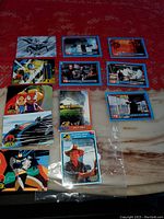 Overview photo showing 20 vintage colored movie collector cards laid out on a table, featuring Jurassic Park, Batman animated series, and various animated titles.