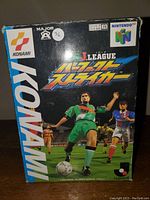 Front cover of the J. League soccer game box for Nintendo 64 showing Konami branding and illustrated soccer players.