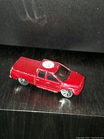 Photo of red miniature Dodge Ram truck model showing front and side with some paint wear visible.
