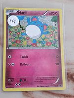 Close up photo of Marill Basic Pokemon card with holo foil background, showing artwork, stats, and moves.