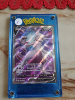 Front view of rare Mewtwo V holographic Pokemon card in blue screw-secured protective case on marble background.