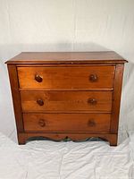 Front view of antique wooden dresser showing all three drawers and wood knob pulls.